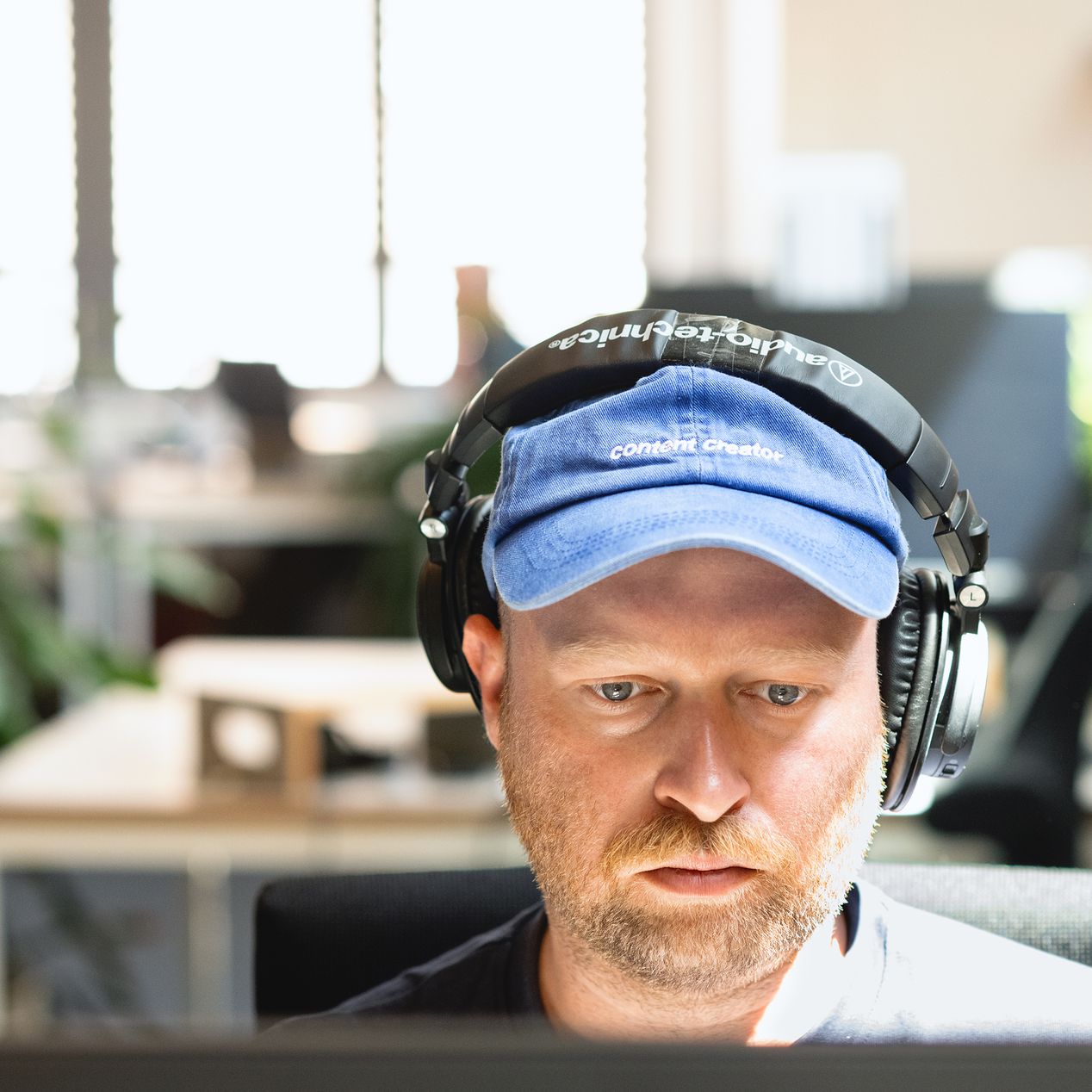 Ein Mitarbeitender von Labor b arbeitet konzentriert am Bildschirm und hört dabei über Kopfhörer Musik.