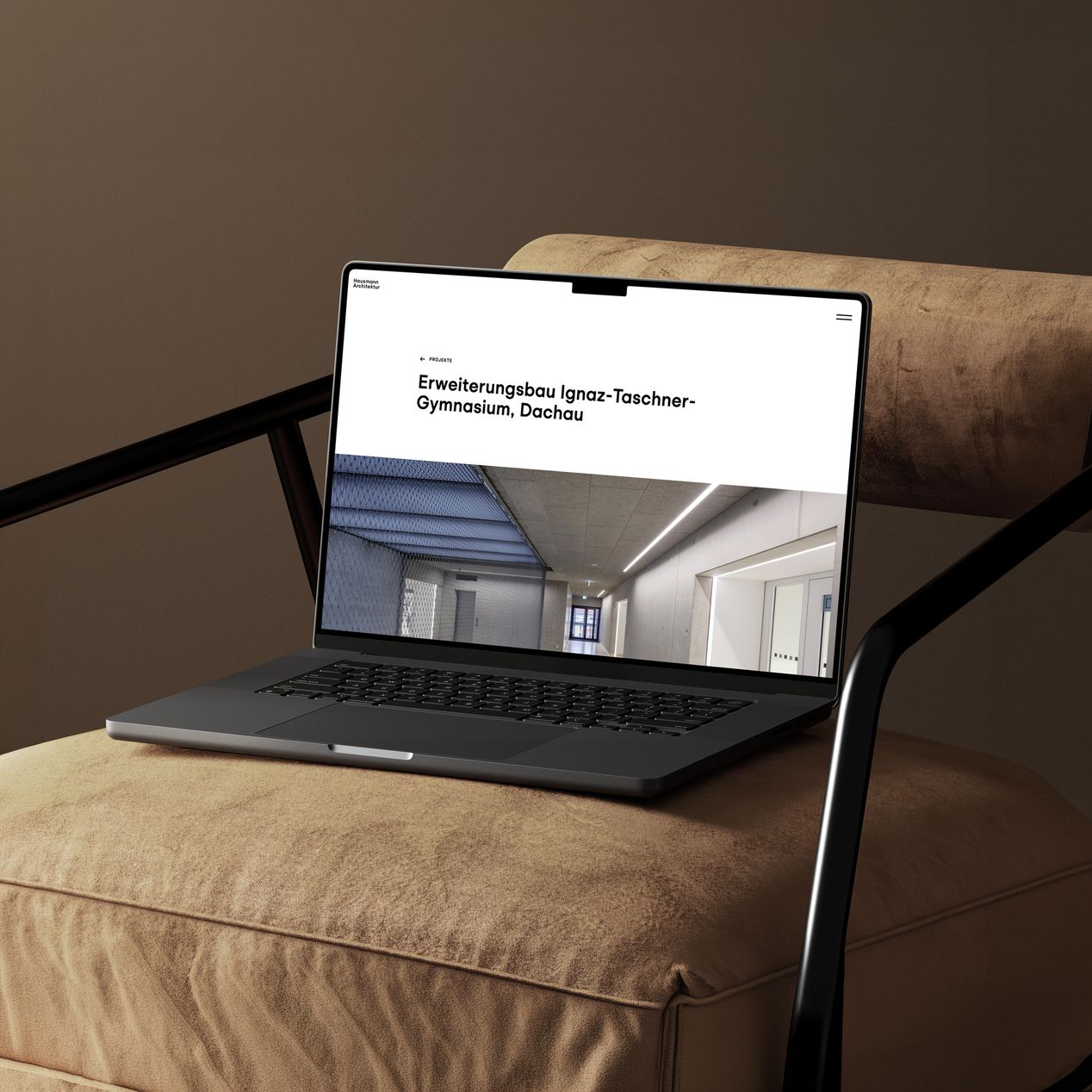 Auf einem Designer-Sessel steht ein Laptop, auf dem die von Labor b entwickelte Website von Hausmann Architektur zu sehen ist.