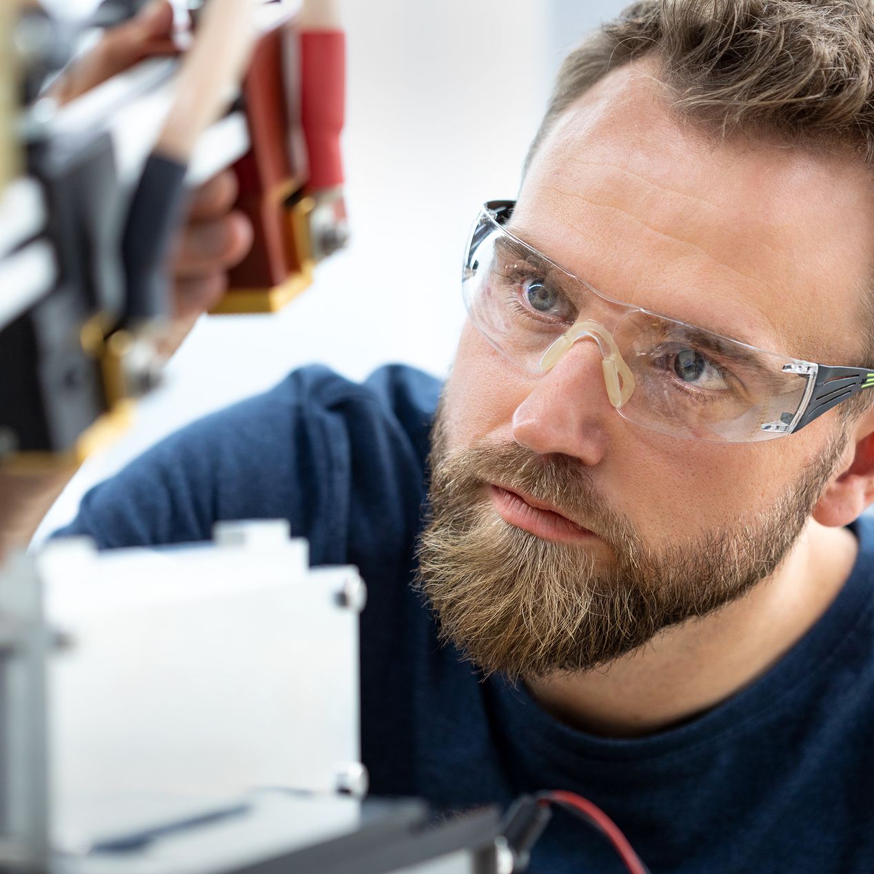 Ein Voltavision-Mitarbeiter mit Schutzbrille arbeitet konzentriert an einer technischen Vorrichtung.