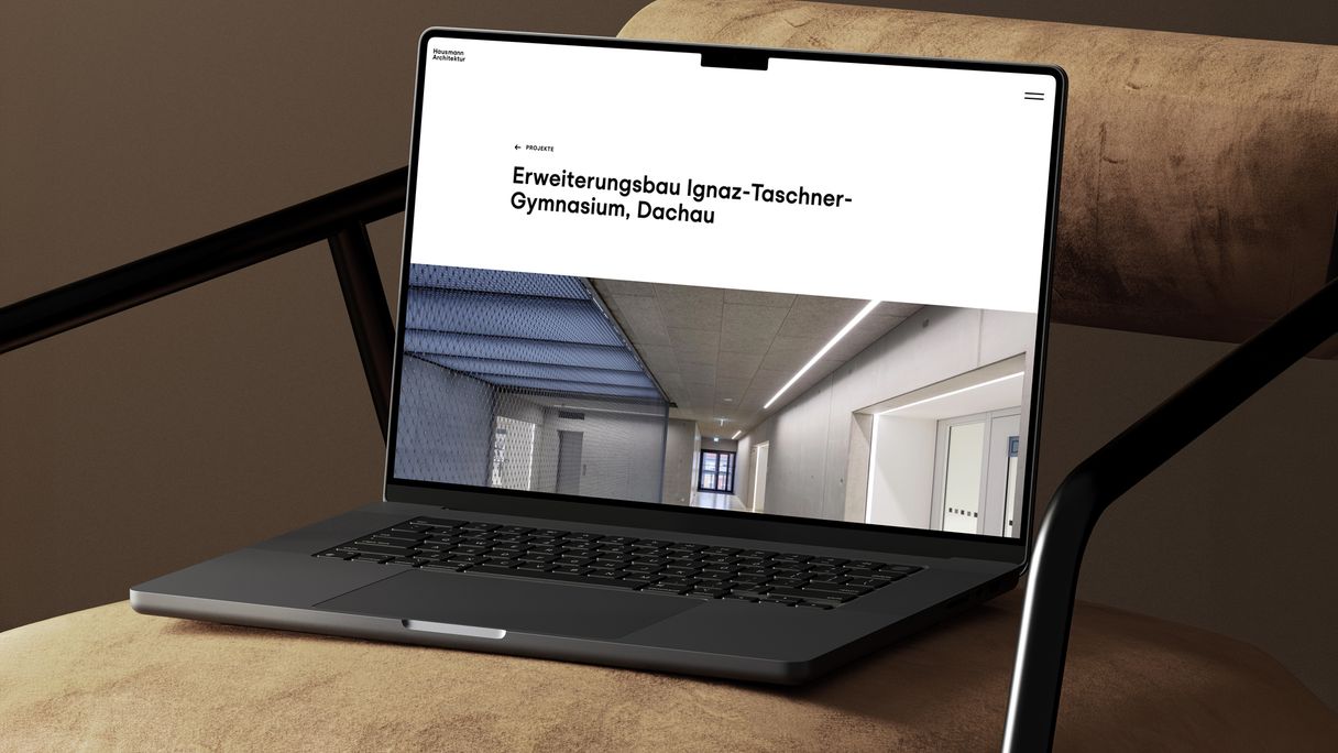 Auf einem Designer-Sessel steht ein Laptop, auf dem die von Labor b entwickelte Website von Hausmann Architektur zu sehen ist.