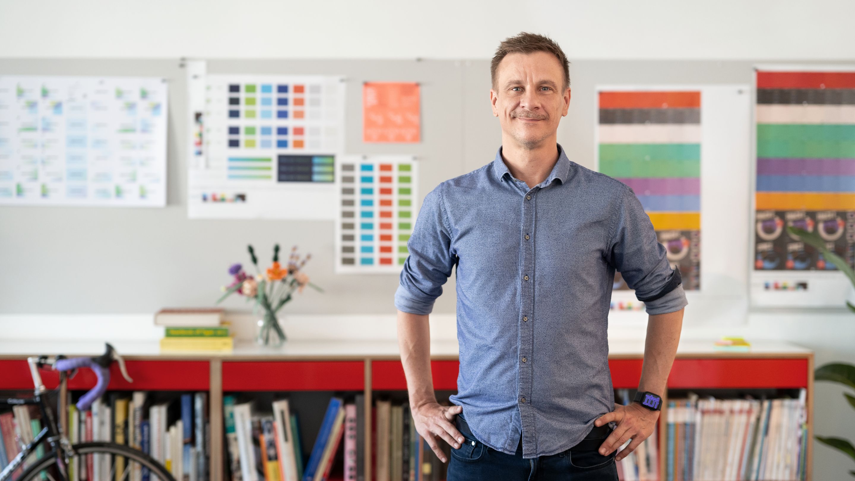 Labor b-Geschäftsführer Björn Rüther steht erwartungsvoll in den Agentur-Räumen vor einer Magnetwand mit Design-Entwürfen.
